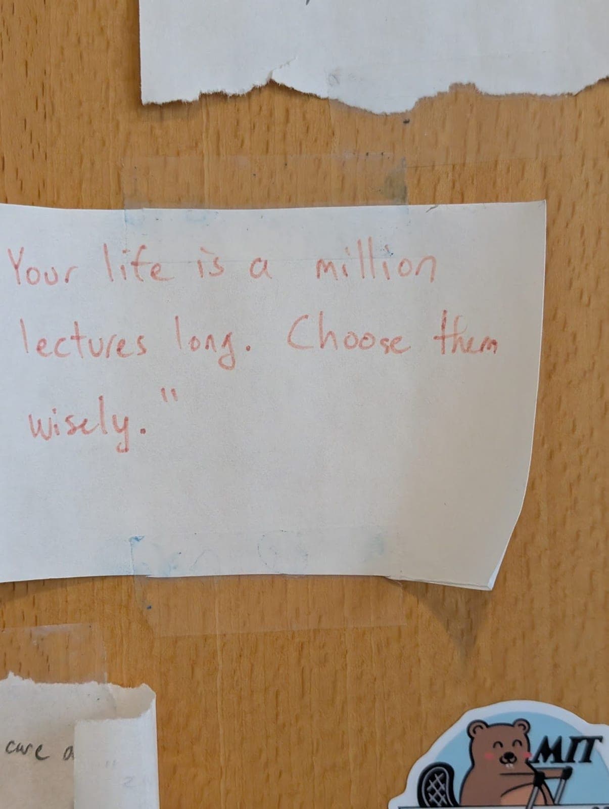 A handwritten note taped to the door, next to an MIT beaver sticker.