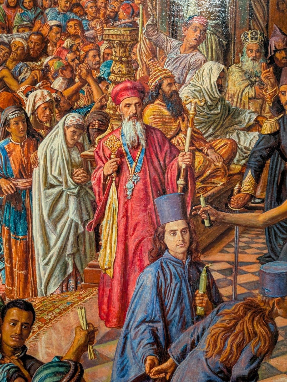 Detail of a crowded, colourful painting of people in robes and crowns, one holding a cross.