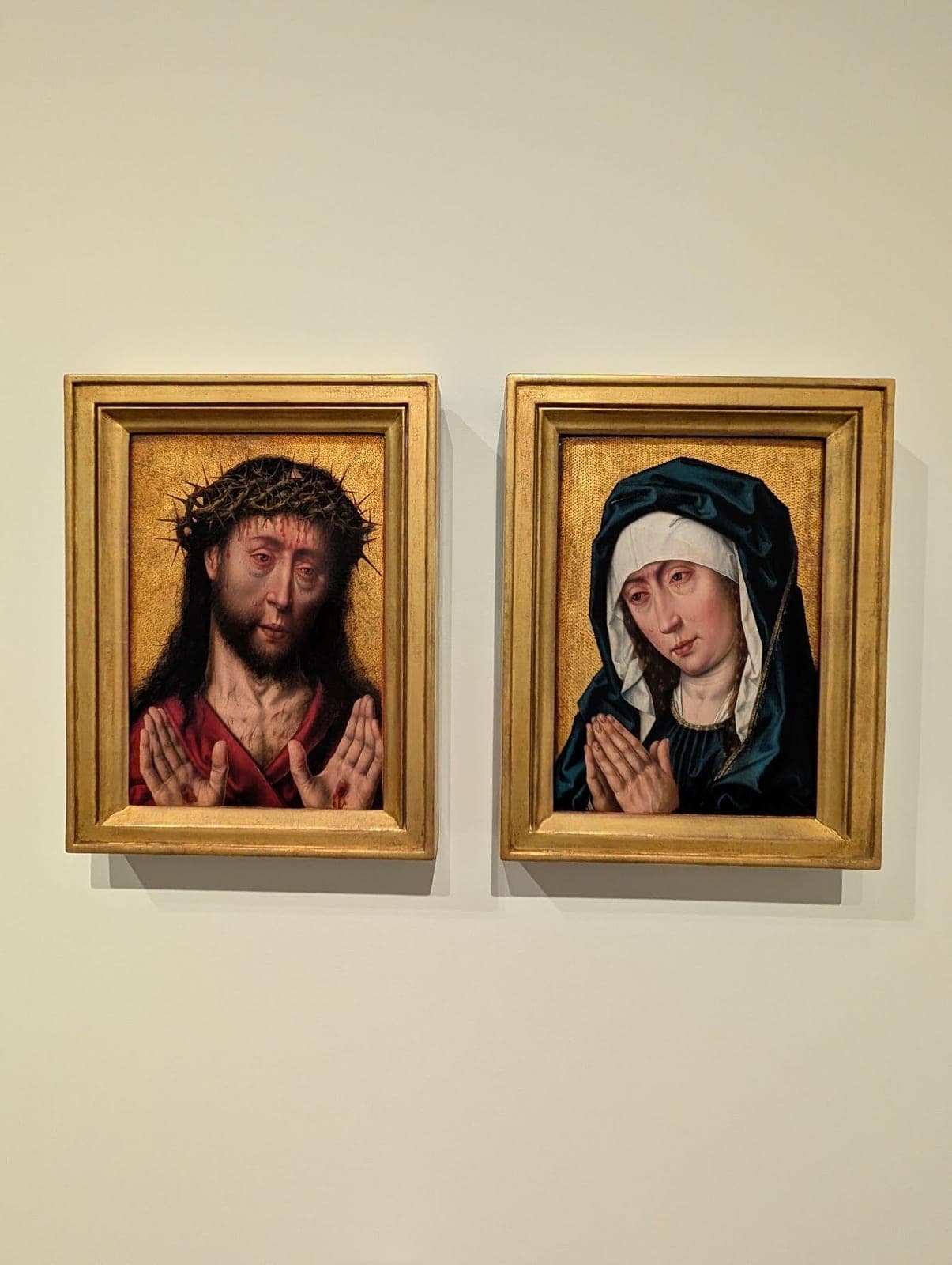 Two small gold-framed paintings side by side: Christ in a crown of thorns showing his wounds, and Mary weeping with her hands pressed together.