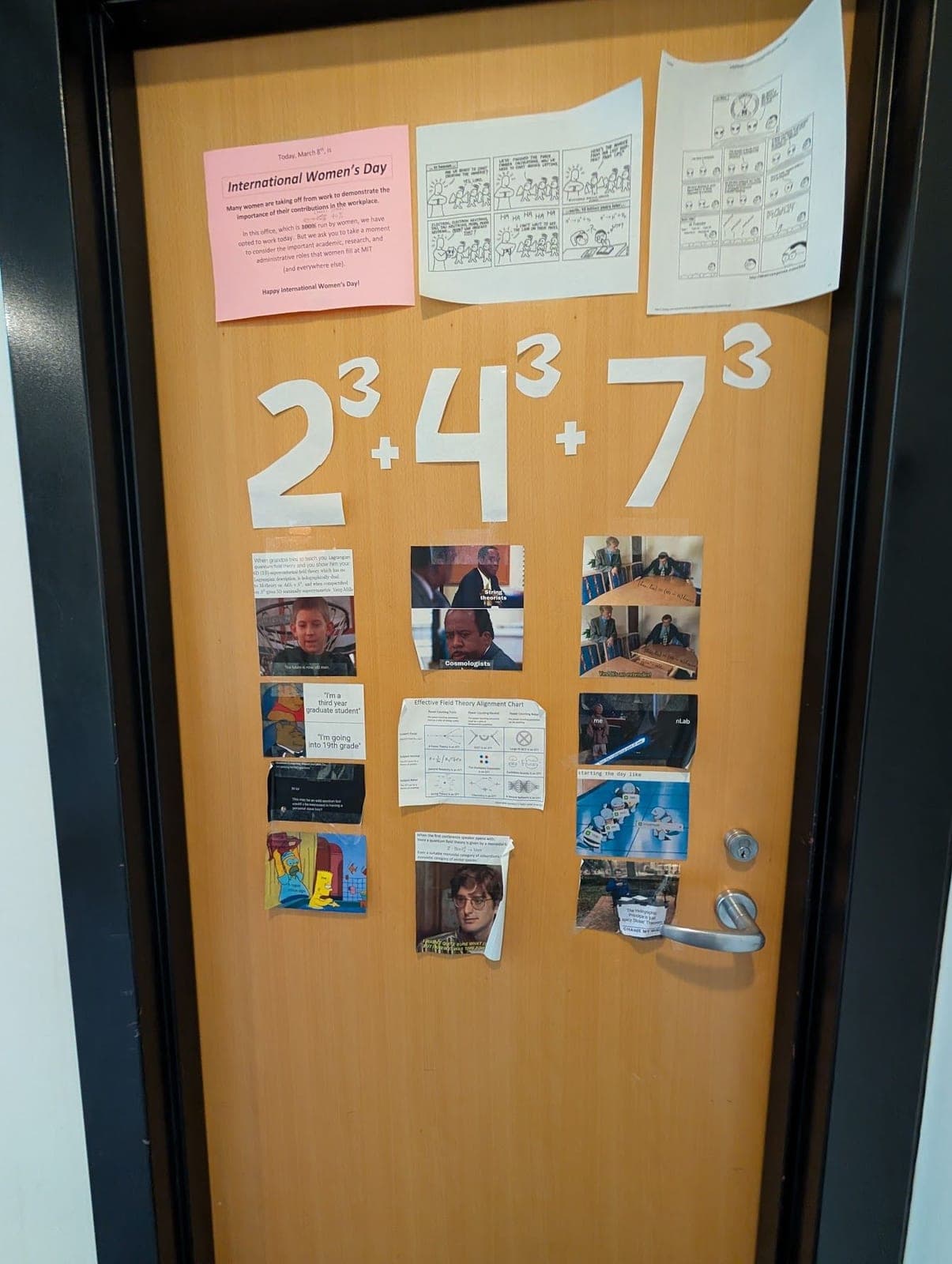 An office door covered in notes and photos, with 2³ + 4³ + 7³ written large across it.