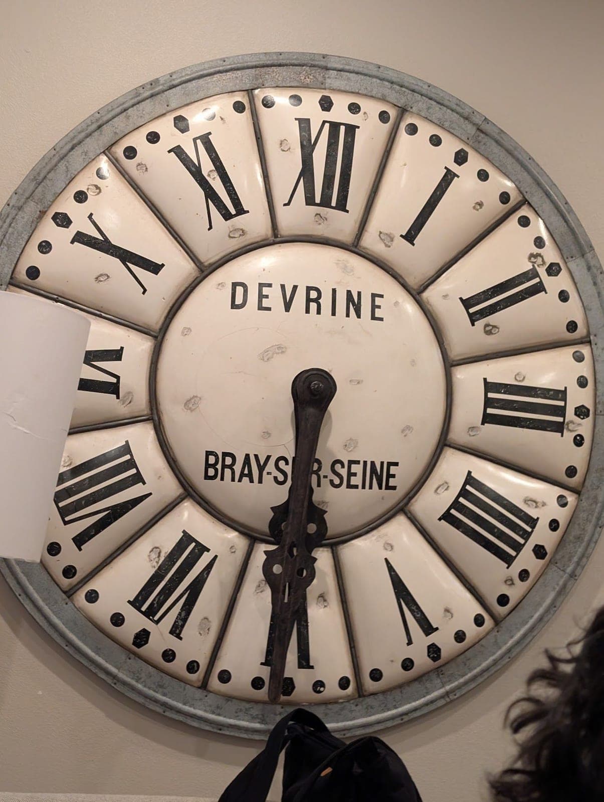 A big old clock face with black Roman numerals, reading Devrine, Bray-sur-Seine.
