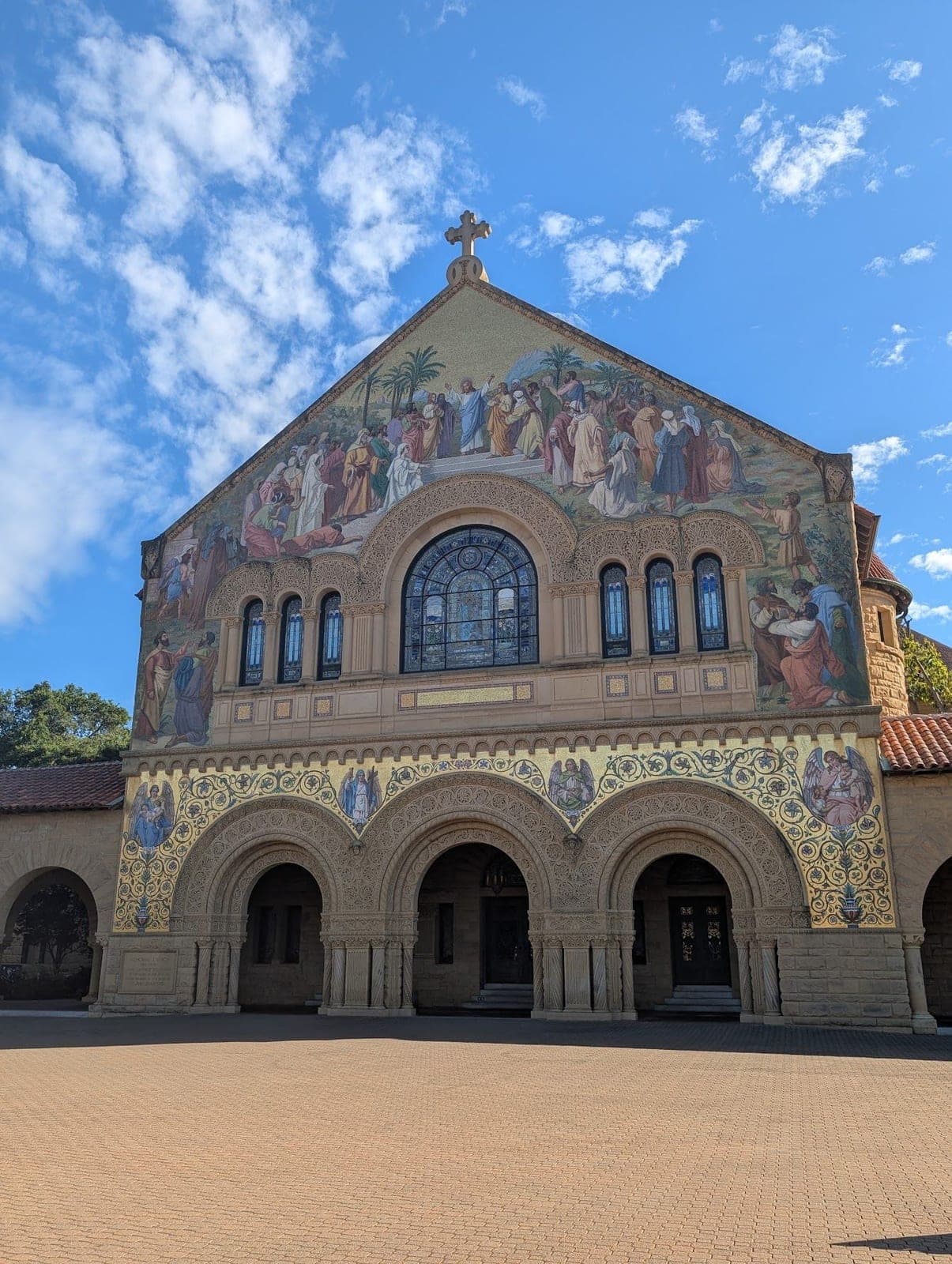 The gold mosaic front of Stanford Memorial Church under a blue sky with little clouds.