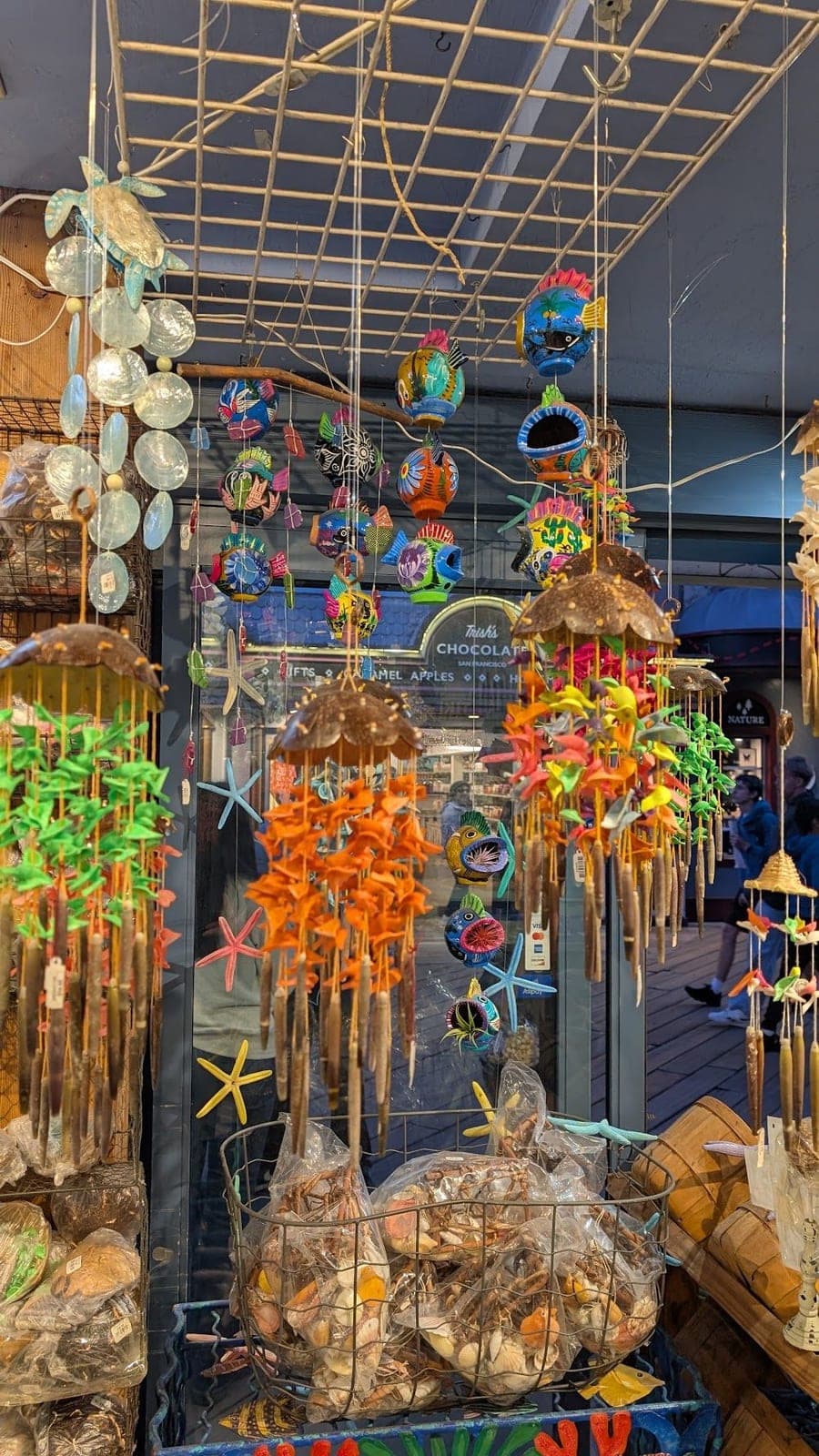 Shell wind chimes and colourful hanging decorations at a seaside shop.