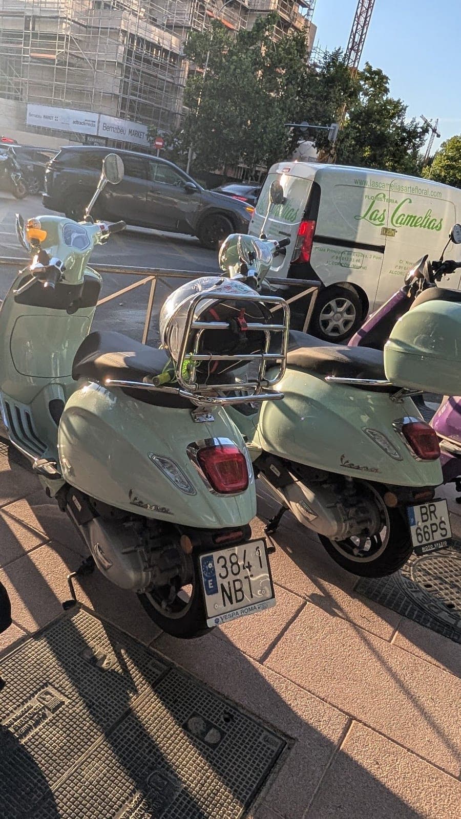 Two mint green Vespa scooters parked on a sunny street.